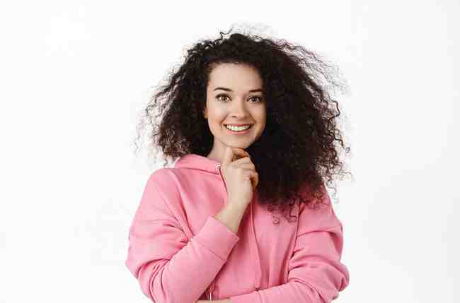 image confident brunette woman touch chin smiling looking determined camera standing hoodie against white background have interesting idea (1)
